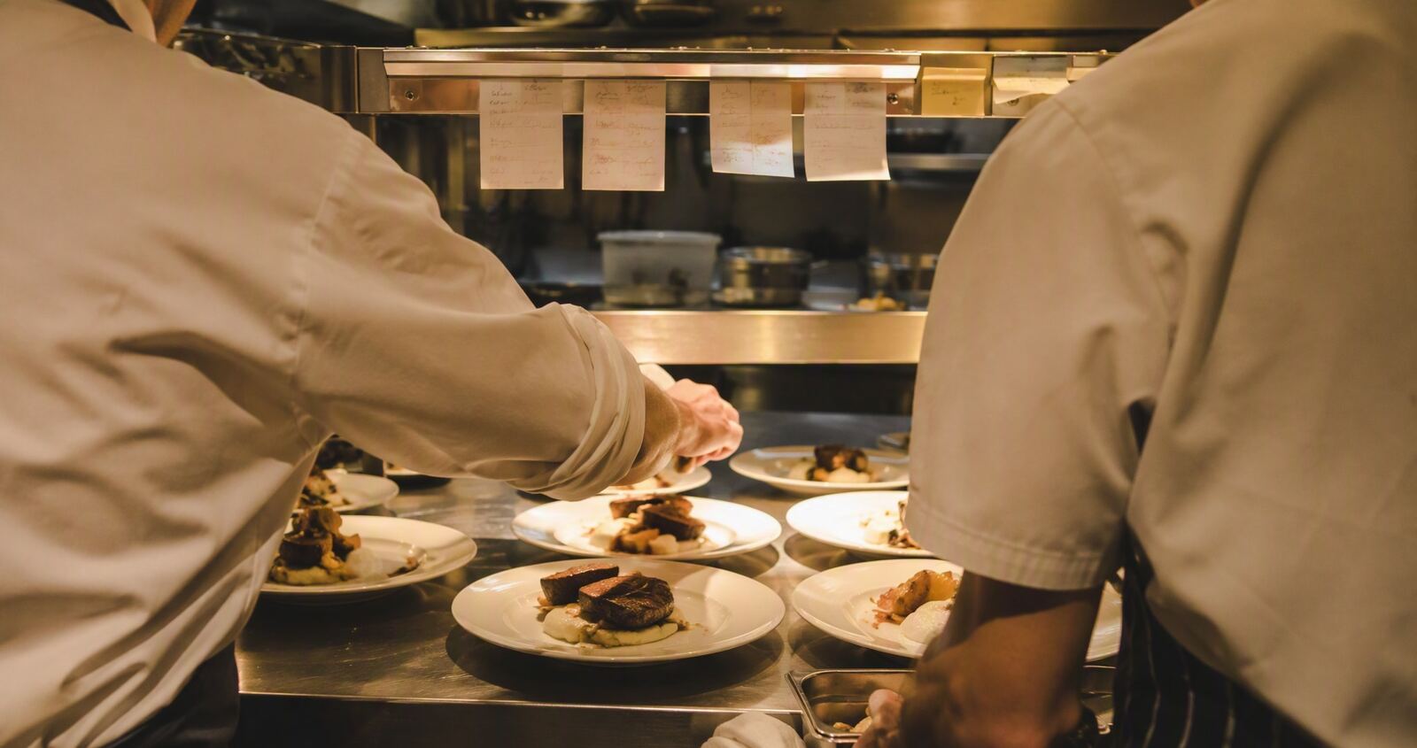Chefs plating dishes at the pass during a private dinner service